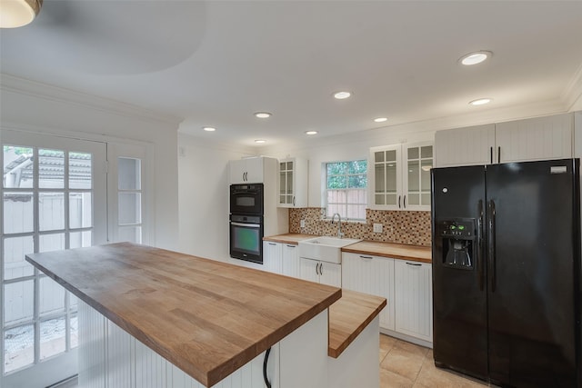 kitchen featuring butcher block counters, a sink, decorative backsplash, black appliances, and crown molding