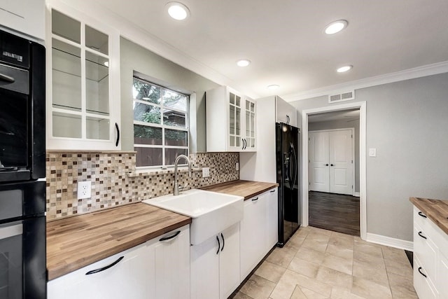 kitchen with visible vents, wooden counters, ornamental molding, a sink, and black appliances