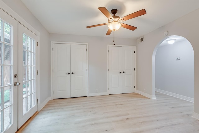 interior space with arched walkways, two closets, visible vents, and light wood-style floors