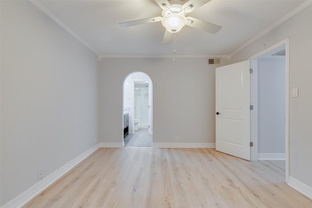 spare room featuring arched walkways, visible vents, baseboards, ornamental molding, and light wood finished floors