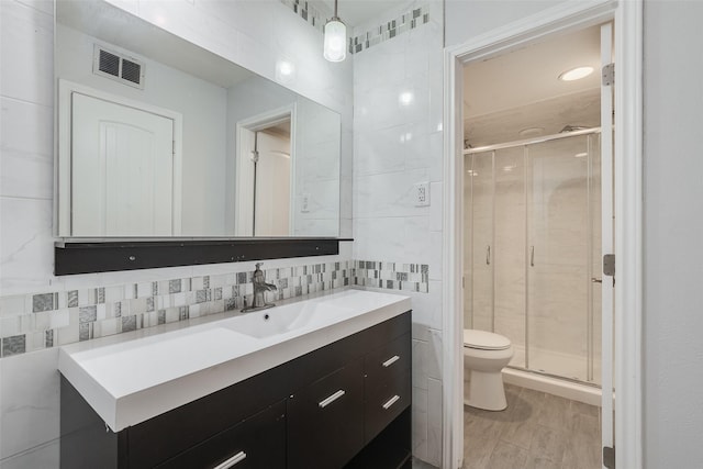 full bath featuring a stall shower, visible vents, toilet, vanity, and tile walls