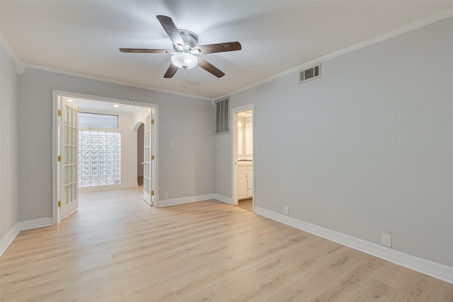 empty room featuring ornamental molding, arched walkways, visible vents, and light wood finished floors