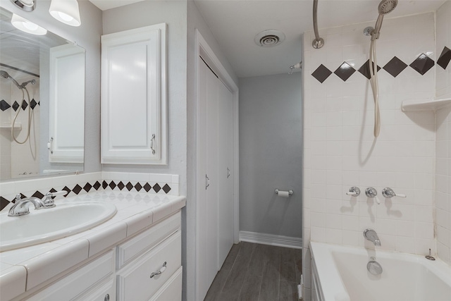 bathroom with wood finished floors, vanity, visible vents,  shower combination, and decorative backsplash