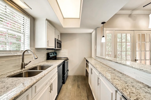 kitchen with stainless steel appliances, tasteful backsplash, a sink, and white cabinets