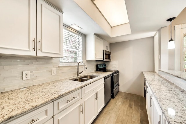 kitchen with stainless steel appliances, backsplash, a sink, and white cabinets