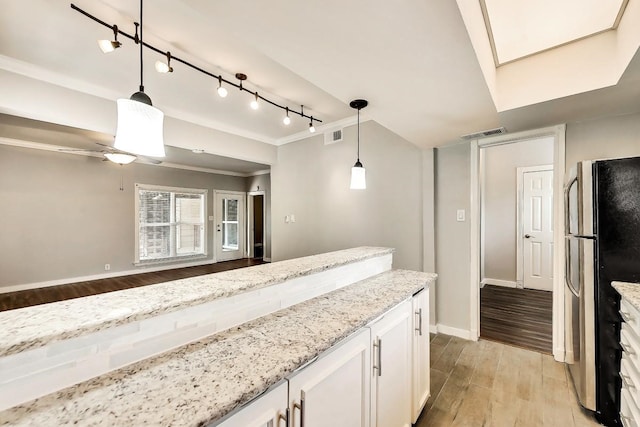 kitchen with light stone countertops, light wood-style floors, visible vents, and freestanding refrigerator