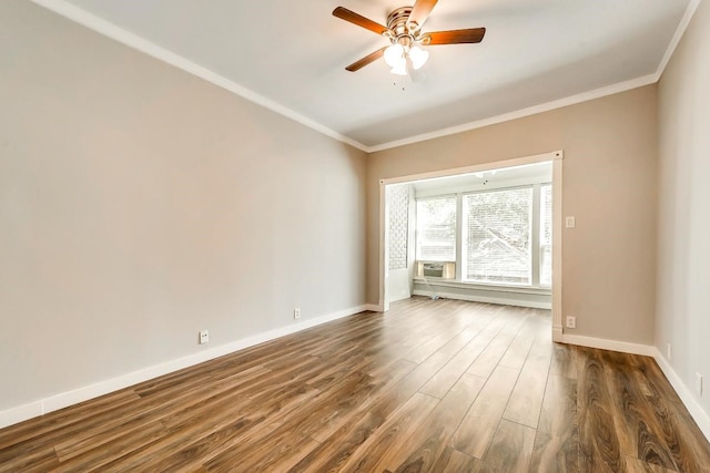 empty room with ornamental molding, dark wood-style flooring, baseboards, and a ceiling fan