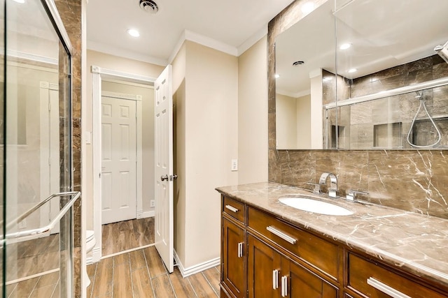 bathroom featuring visible vents, crown molding, vanity, wood finish floors, and backsplash