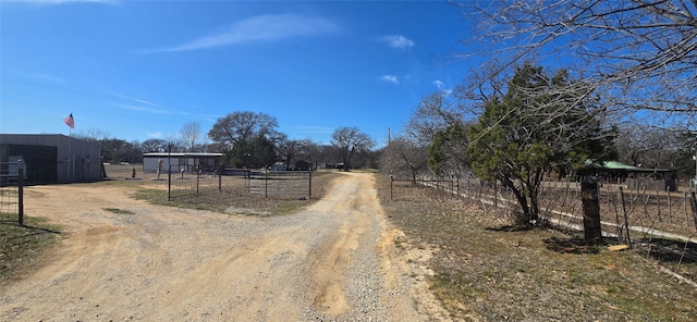 view of street featuring a rural view, driveway, and a gated entry