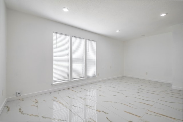 empty room featuring recessed lighting, marble finish floor, and baseboards