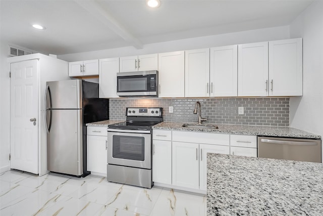 kitchen featuring appliances with stainless steel finishes, marble finish floor, a sink, and tasteful backsplash