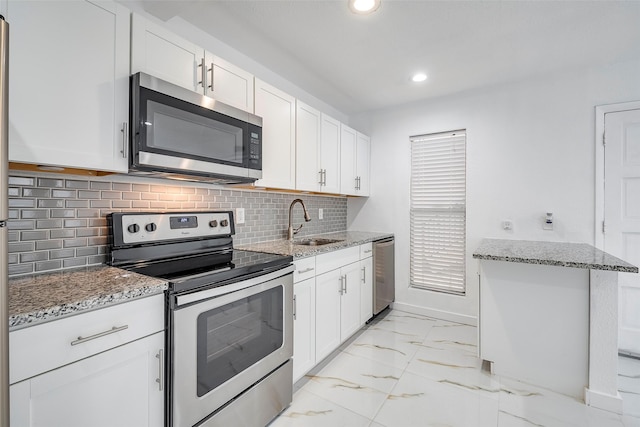 kitchen featuring marble finish floor, stainless steel appliances, stone counters, and a sink