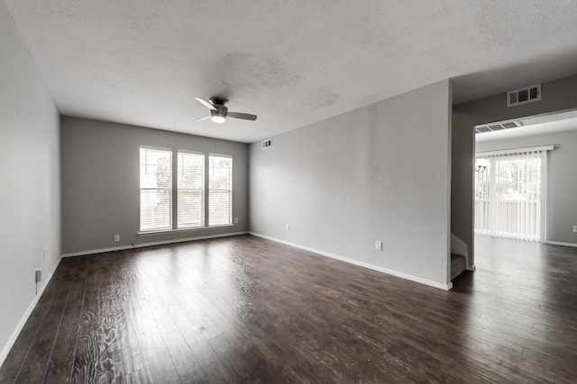 unfurnished room with a textured ceiling, visible vents, baseboards, a ceiling fan, and dark wood finished floors