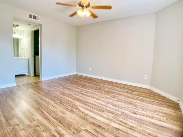 spare room featuring light wood-type flooring, baseboards, visible vents, and a ceiling fan