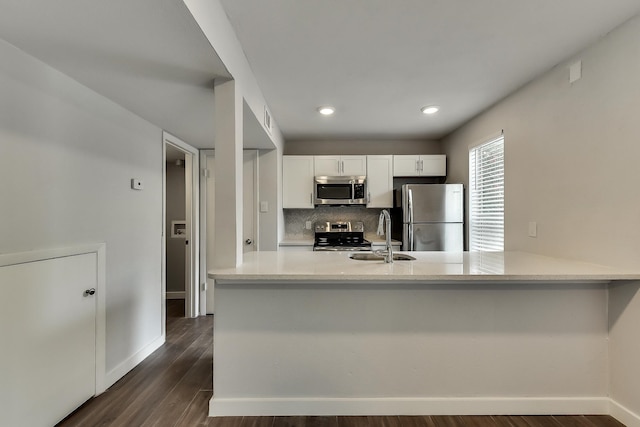 kitchen featuring stainless steel appliances, dark wood-type flooring, a sink, white cabinets, and decorative backsplash