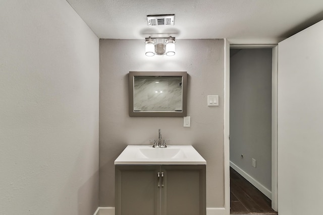 bathroom with baseboards, visible vents, wood finished floors, a textured ceiling, and vanity