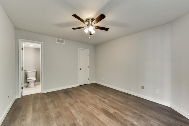 unfurnished bedroom featuring baseboards, connected bathroom, visible vents, and wood finished floors