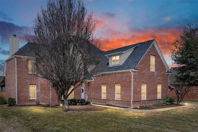 view of front of property with a front lawn, brick siding, and a chimney