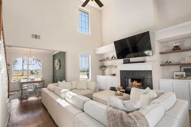 living area featuring dark wood-style floors, visible vents, plenty of natural light, and a tile fireplace