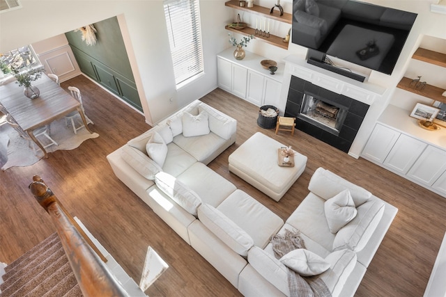 living room with visible vents, stairs, a tile fireplace, wood finished floors, and a decorative wall