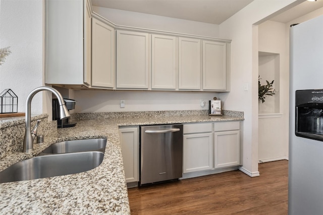 kitchen featuring dark wood-type flooring, baseboards, light stone counters, stainless steel fridge, and a sink