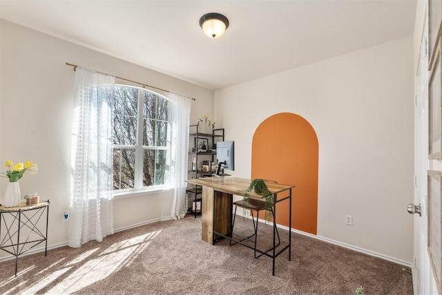 carpeted office featuring arched walkways and baseboards