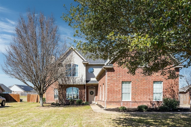 view of front of property with brick siding, a front yard, and fence