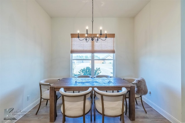 dining space featuring light wood-type flooring, baseboards, and a notable chandelier