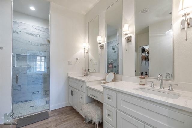 full bath featuring a stall shower, visible vents, a sink, and wood finished floors