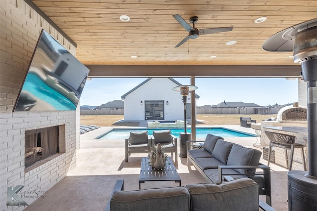 view of patio / terrace featuring ceiling fan, an outdoor living space with a fireplace, fence, and a pool with connected hot tub