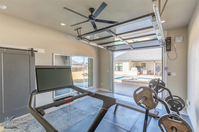 interior space with ceiling fan, a barn door, and baseboards