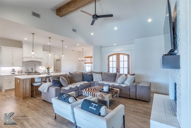 living room with visible vents, beamed ceiling, french doors, light wood-type flooring, and a fireplace