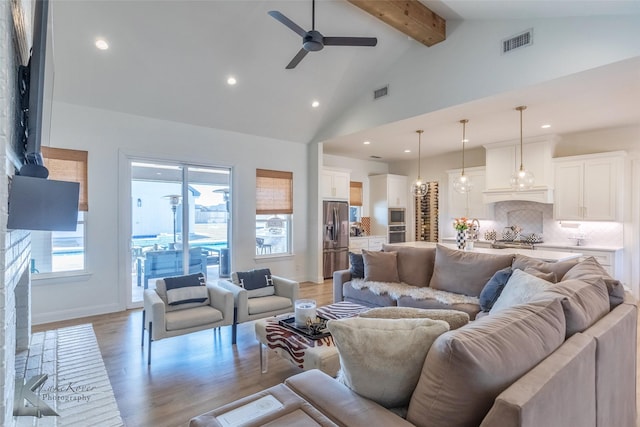 living room featuring light wood-type flooring, high vaulted ceiling, visible vents, and beam ceiling