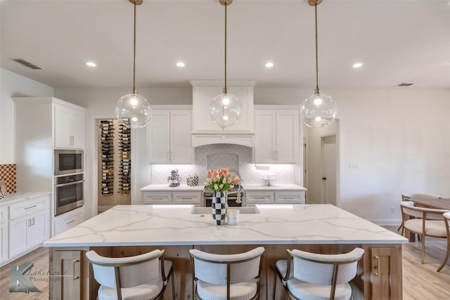 kitchen with stainless steel appliances, a sink, visible vents, and white cabinetry