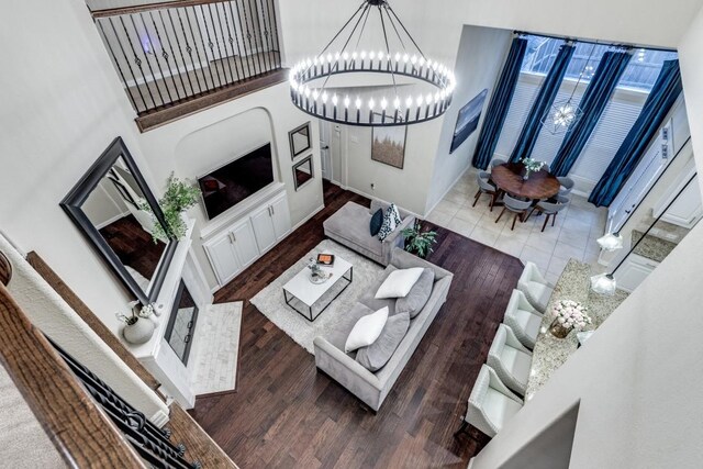 living area featuring a high ceiling, a fireplace, wood finished floors, and recessed lighting