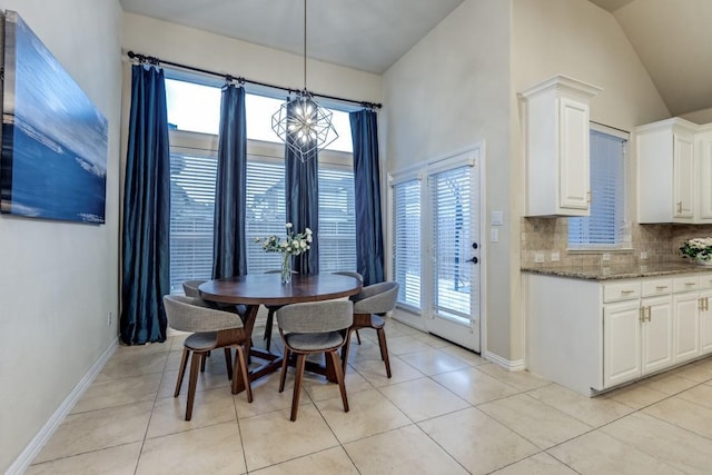 dining room featuring baseboards, vaulted ceiling, light tile patterned flooring, and an inviting chandelier