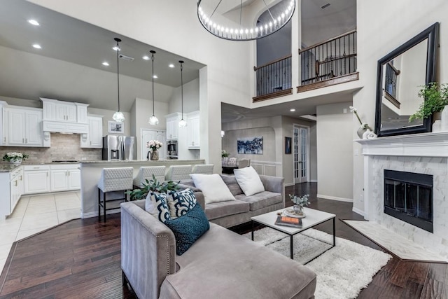 living area featuring recessed lighting, a fireplace with flush hearth, a towering ceiling, and light wood finished floors