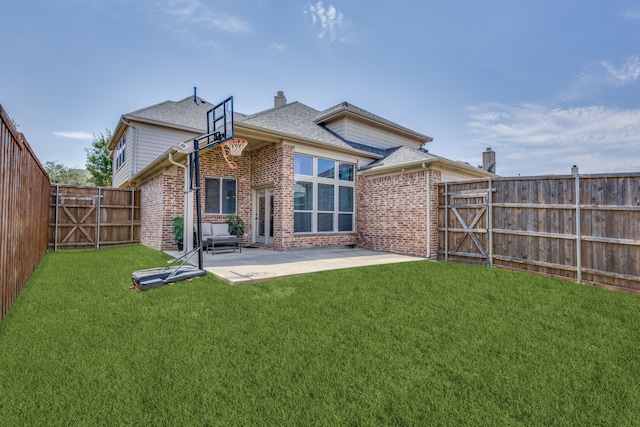 rear view of house featuring a gate, brick siding, a lawn, and a patio