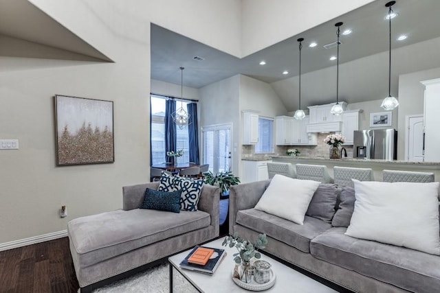 living area with dark wood-style floors, recessed lighting, baseboards, and a high ceiling