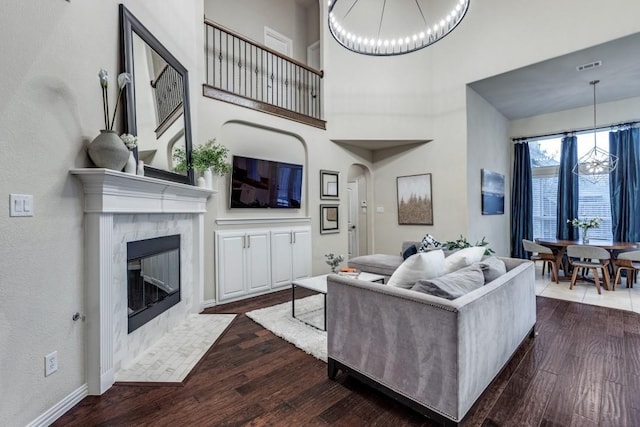 living area featuring dark wood-style floors, a fireplace, and a notable chandelier