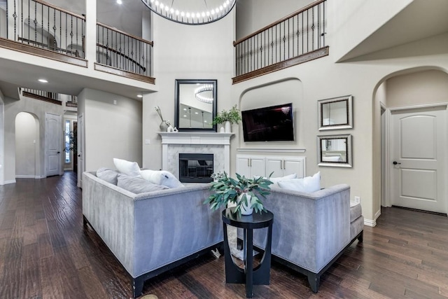 living room with arched walkways, hardwood / wood-style floors, a glass covered fireplace, and baseboards