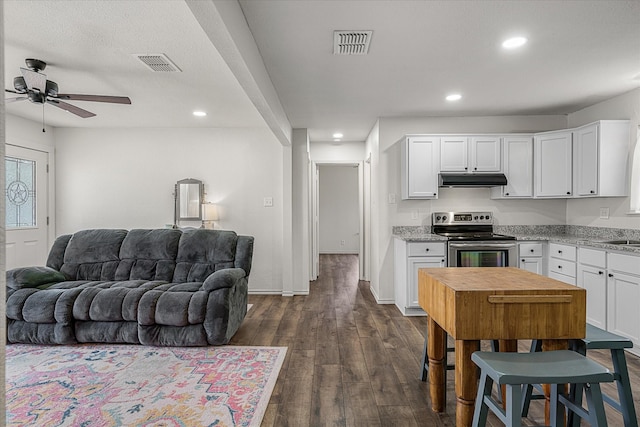 kitchen featuring dark wood-style flooring, visible vents, stainless steel electric range oven, and white cabinetry