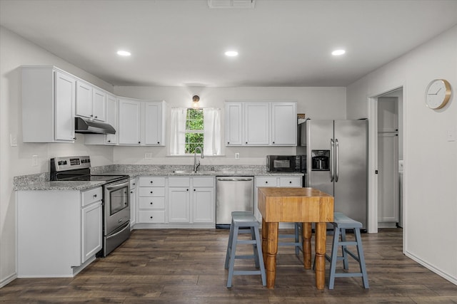 kitchen with stainless steel appliances, under cabinet range hood, light stone counters, and dark wood-style floors