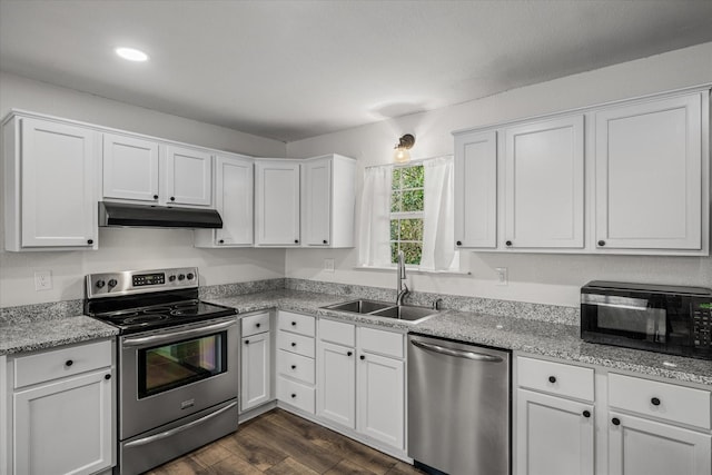 kitchen with white cabinets, dark wood-style floors, appliances with stainless steel finishes, under cabinet range hood, and a sink