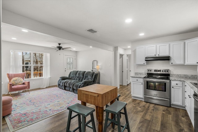 kitchen with dark wood-style flooring, visible vents, under cabinet range hood, and stainless steel electric stove