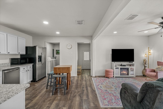 kitchen featuring visible vents, open floor plan, stainless steel appliances, washing machine and dryer, and white cabinetry