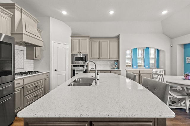 kitchen featuring lofted ceiling, a sink, appliances with stainless steel finishes, dark wood-style floors, and an island with sink