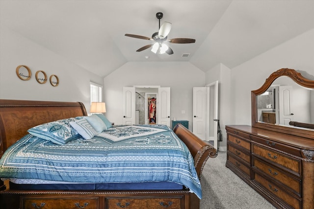 carpeted bedroom with vaulted ceiling, a walk in closet, and a ceiling fan