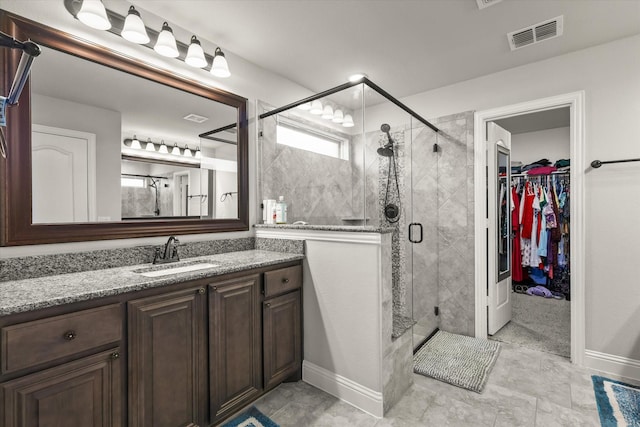 full bathroom featuring a spacious closet, a stall shower, vanity, and visible vents