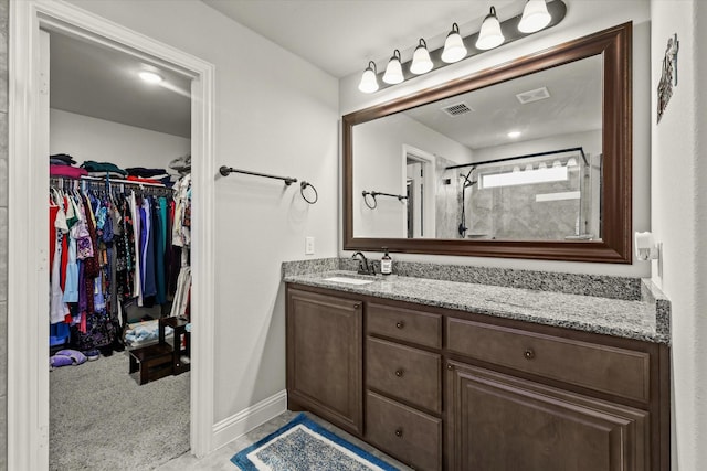 full bathroom featuring a shower stall, visible vents, a walk in closet, and vanity